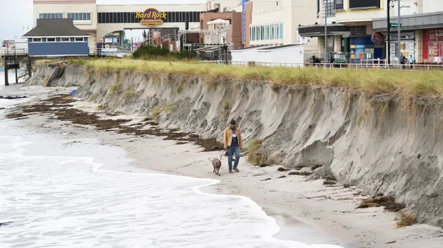 A man walks his dog near beach erosion along the Atlantic City shoreline on Monday, Sept. 28, 2026, following a severe nor’easter over the weekend.