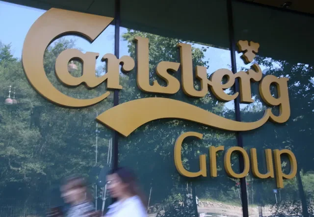 Pedestrians walk past a sign for the Carlsberg Group at their office in Copenhagen, Denmark, August 13, 2025. REUTERS/Tom Little
