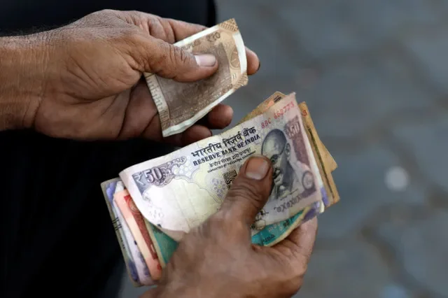 صورة أرشيفية: أمين صندوق يحمل أوراقاً نقدية للعملة الهندية في محطة وقود في أحمد آباد، الهند، 20 مايو 2026. REUTERS/أميت ديف/ صورة أرشيفية