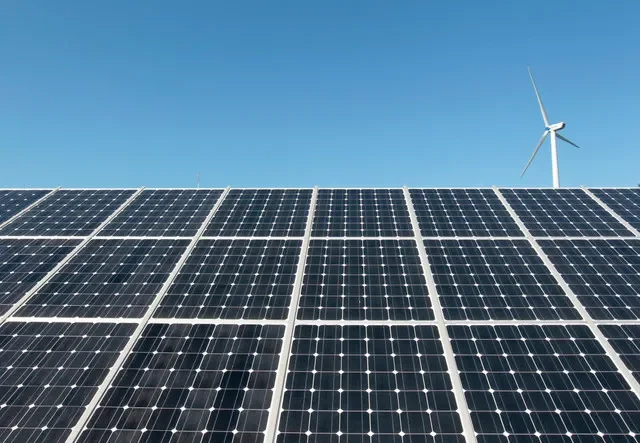 FILE PHOTO: A wind turbine is seen over the panels of a solar power plant in Incheon, about 90 km (55 miles) west of Seoul, September 30, 2010. REUTERS/Jo Yong-Hak/File Photo