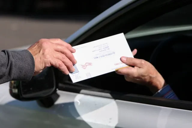 A ballot is handed off at a temporary drive-thru location on Court Street NE on Tuesday, May 19, 2026 in Salem, Ore.