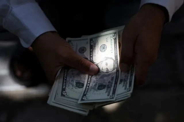 A currency dealer holds U.S. dollar bills in Tehran, Iran, September 27, 2026. Majid Asgaripour/WANA (West Asia News Agency) via REUTERS