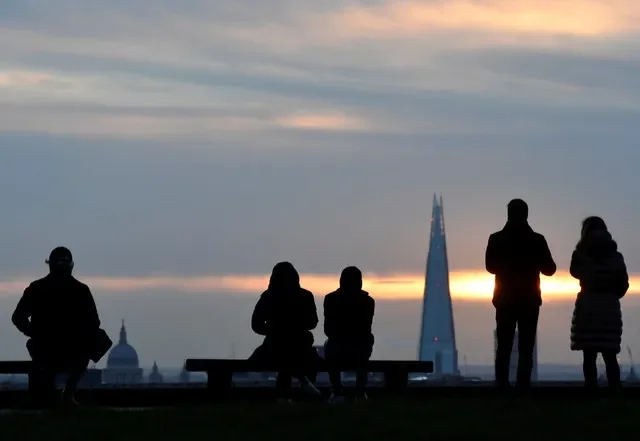People watch the sunrise with the Shard skyscraper and St. Paul's Cathedral visible on the skyline, from Primrose Hill in London, Britain, January 7, 2022. REUTERS/Toby Melville