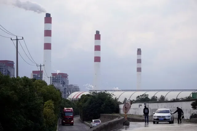 資料照:2021年10月21日,中國上海,幾名男子站在一座燃煤電廠旁的汽車附近。路透社/宋劍/資料照