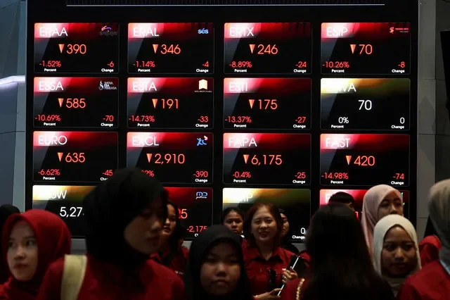 FILE PHOTO: Students walk past an electronic board showing stock market index at the Indonesia Stock Exchange (IDX) in Jakarta, Indonesia, February 2, 2026. REUTERS/Willy Kurniawan/File Photo
