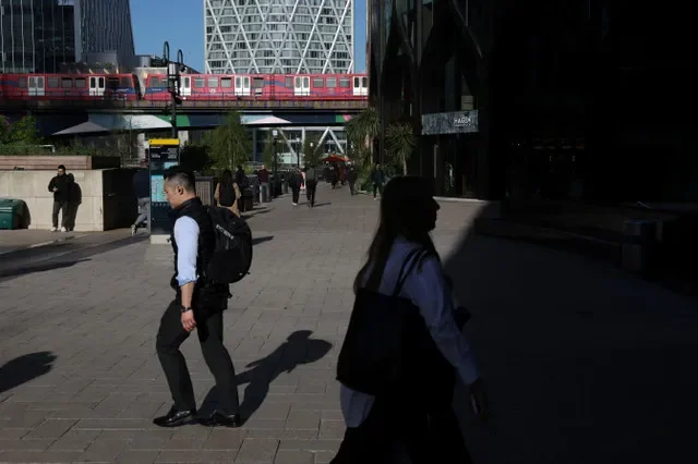 資料照片:2026年4月13日,英國倫敦,碼頭區輕便鐵路列車駛過,行人在金絲雀碼頭金融商業區走過。路透社/凱文·庫姆斯/資料照片