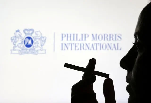 2022年7月26日拍攝的這幅插圖中,一名女性在Philip Morris International標誌前手持香菸擺姿勢。路透社/達多·魯維奇/插圖