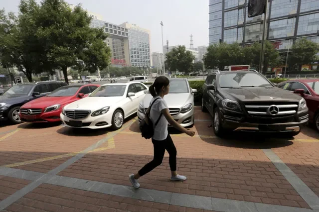 A woman walks past Mercedes Benz cars displayed for sale outside a store in Beijing, China August 11, 2015. REUTERS/Jason Lee