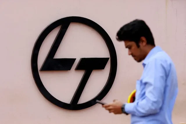An employee checks his phone next to a logo of L&T outside the Larsen & Toubro Precision Manufacturing and Systems complex on the outskirts of Coimbatore, India, February 26, 2025. REUTERS/Sivaram V