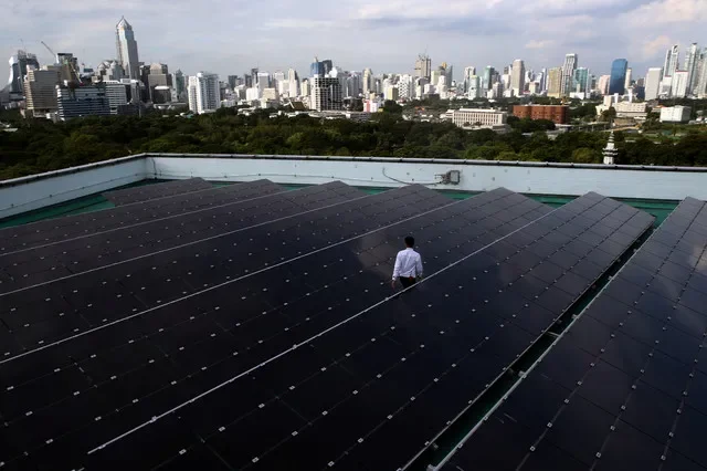 2017年8月9日,泰國曼谷,一名男子走過一棟建築物屋頂上的太陽能板。REUTERS/Athit Perawongmetha