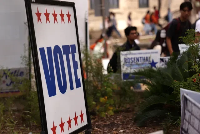 Estudiantes pasan junto a carteles cerca de un centro de votación anticipada en el campus de la Universidad de Texas en Austin durante la votación anticipada previa a las elecciones intermedias de EE. UU. del 3 de noviembre en Austin, Texas, EE. UU., el 27 de octubre de 2026. REUTERS/Mike Segar