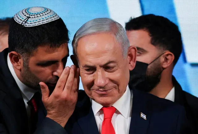 Um assessor conversa com o primeiro-ministro israelense e líder do partido Likud, Benjamin Netanyahu, enquanto ele faz uma declaração após as pesquisas de boca de urna para a eleição nacional de Israel, na sede eleitoral do Likud em Jerusalém, em 28 de outubro de 2026. REUTERS/Ammar Awad