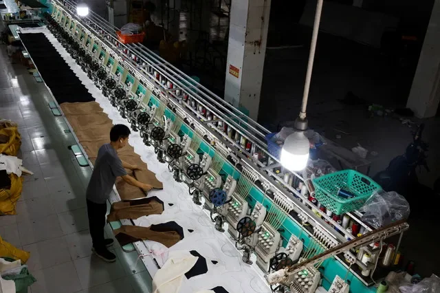 A worker sets up fabric on an automated embroidery machine at a garment factory in Panyu District, Guangzhou, Guangdong province, China, July 27, 2026. REUTERS/Go Nakamura