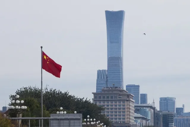 La bandera nacional china ondea frente a los rascacielos del distrito central de negocios mientras los líderes del Partido Comunista de China inauguran la quinta sesión plenaria en Pekín